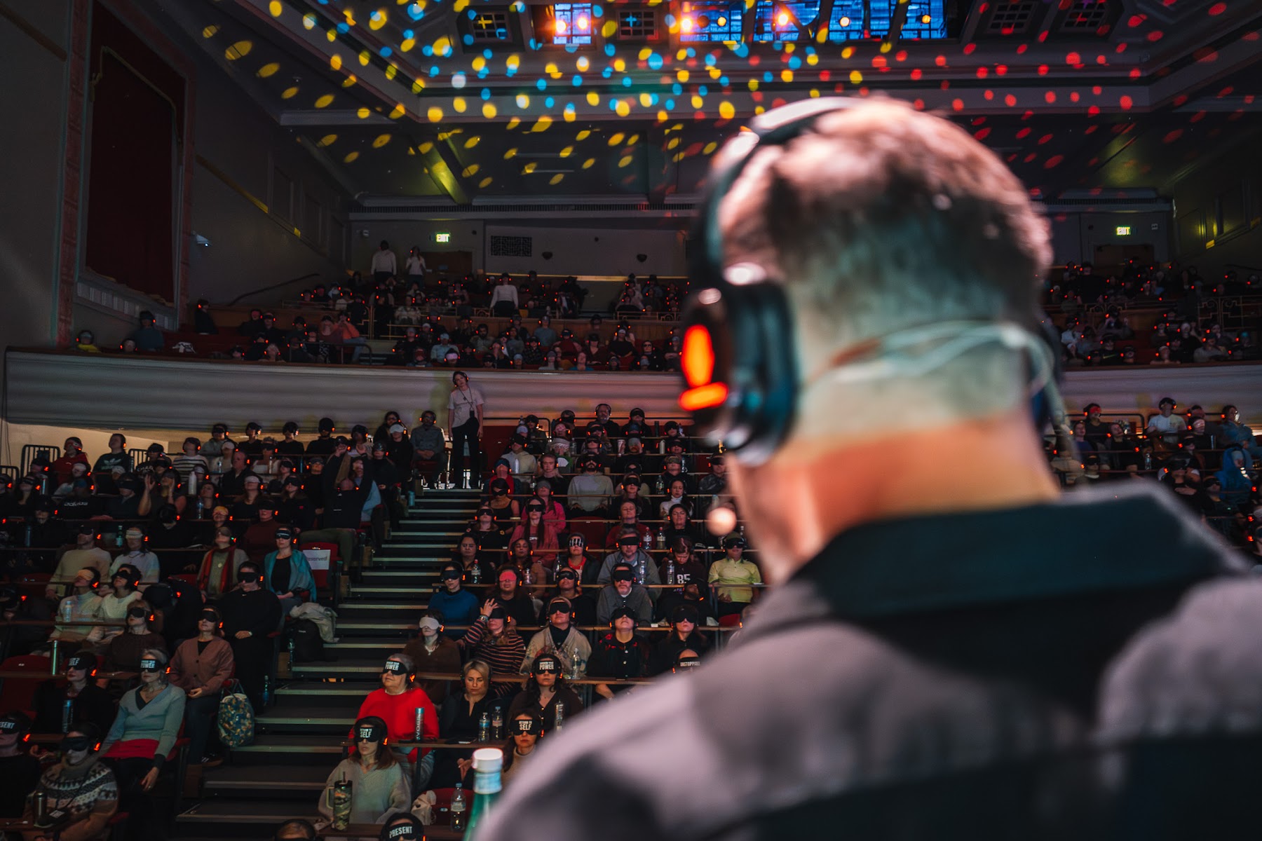 Alexis guiding a breathwork journey from the stage, headphones on