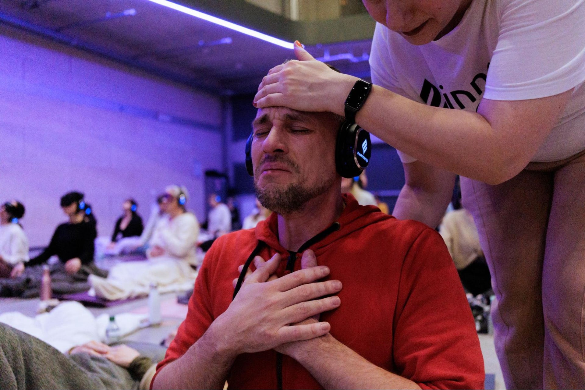 A facilitator provides comforting touch to a participant experiencing deep emotional release during breathwork.