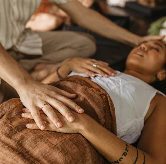 A trauma-informed holistic practitioner offering gentle bodywork support during a supervised somatic healing session.