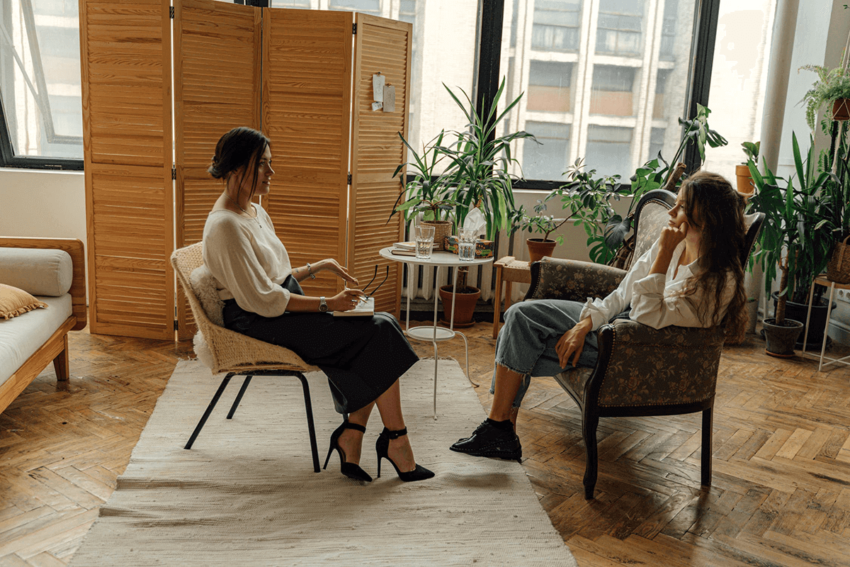 Facilitator and client seated in conversation, representing talk therapy for emotional insight and mental wellness support