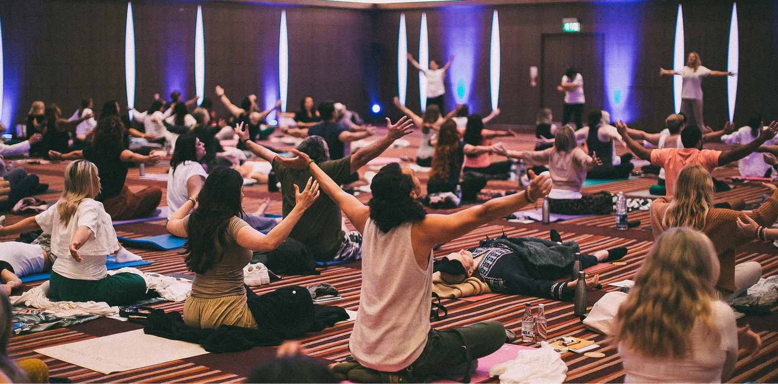 Large group practicing somatic healing with guided movement, breathwork and body awareness in a workshop setting