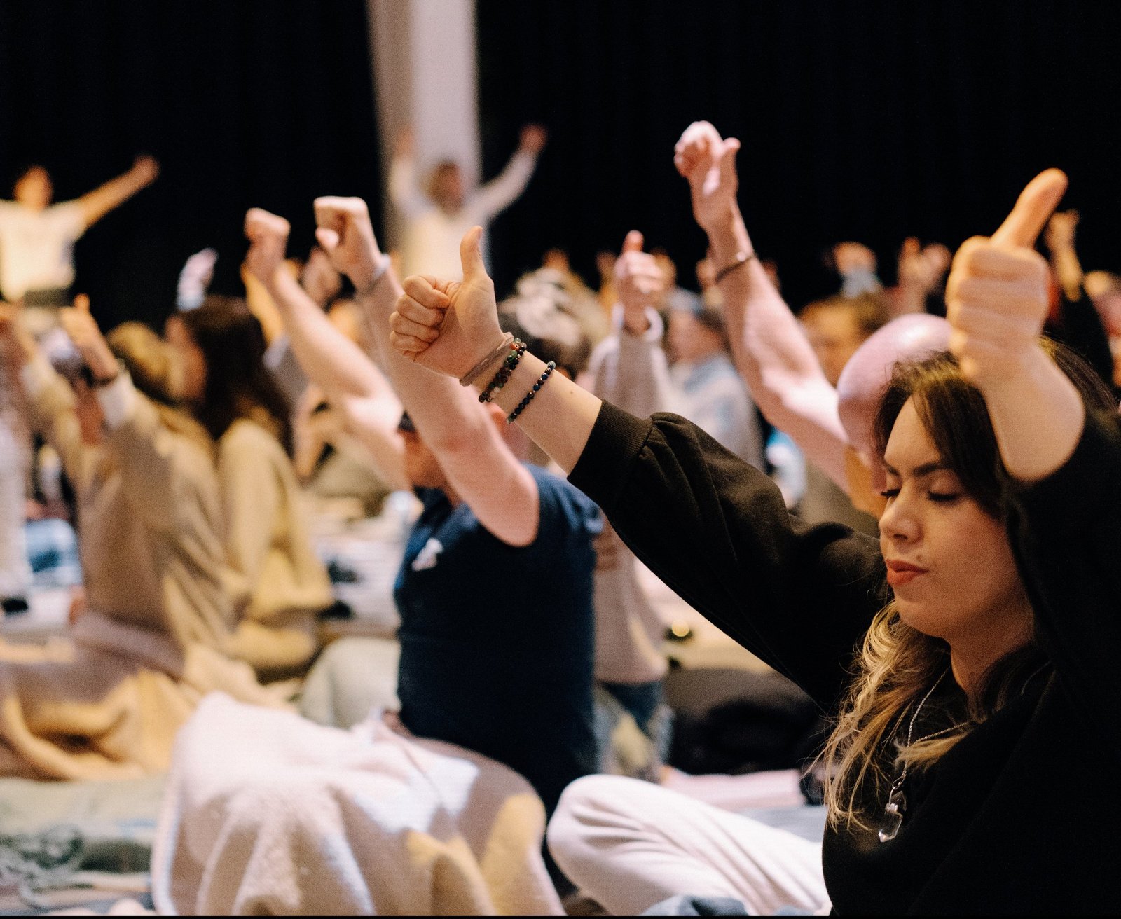 Participants raising their arms in release during a breathwork session