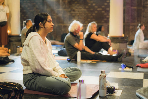 Woman sitting cross legged among a group of attentive participants, listening during a breathwork integration circle