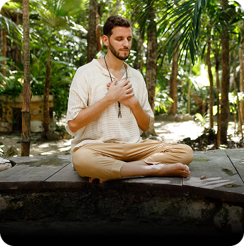 Man meditating in a tropical setting with greenery